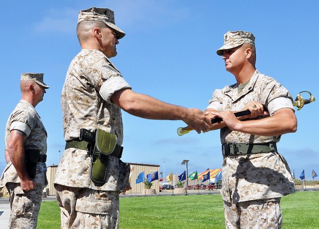 Col. Benjamin Stinson, MCTSSA commanding officer, passes a ceremonial sword to MCTSSA's new sergeant major, Brandon Hall, symbolizing the transfer of duties from outgoing Sgt. Maj. Kenneth Warren during the activity's relief and appointment ceremony Aug. 14 at Camp Pendleton, California. The sword, as the oldest form of weapon still in use, has come to symbolize material leadership. 