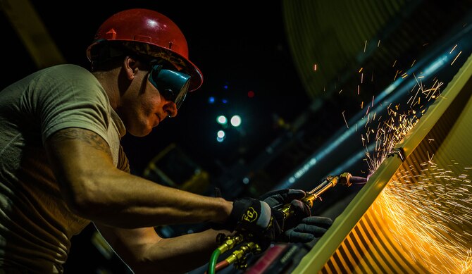 Staff Sgt. Jesse Mitchell cuts a metal structure with a blow torch Aug. 3, 2014, in Southwest Asia. Airmen from the 557th Expeditionary RED HORSE Squadron came from Al Udeid Air Base, Qatar to establish more permanent structures than the current tents used as passenger terminals. The unit is composed of Pennsylvania Air National Guard members deployed in support of Operation Enduring Freedom. Mitchell is a 557th Expeditionary RED HORSE Squadron pavement and equipment operator. (U.S. Air Force photo/Staff Sgt. Jeremy Bowcock)
