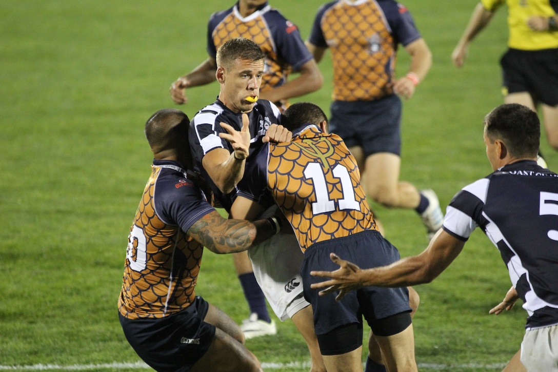 Coast Guard Petty Officer 3d Class Alex Vinkavich (center black/white) is tackled by Navy's Seaman Urban Iyo (#11). Coast Guard would defeat the Navy 14-10 at the 2014 Armed Forces Rugby 7’s Championship in Glendale, Colo. 15-17 August.