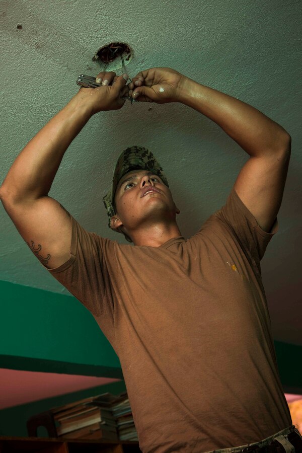 U.S. Navy Construction Electrician 2 Arthur Bernahl,  a Seabee from Construction Battalion Maintenance Unit 202, rewires a light socket to fit a new type of light. The Guatemalan Brigada de Infanteria de Marina (BIM) engineers along with their U.S. counterparts help renovate the Biblioteca Municipal Corporacion 74-78 as part of a humanitarian engineering project in Puerto Barrios, Guatemala, Aug. 14, 2014. The Marines and Sailors are helping to remodel buildings in support of Southern Partnership Station 2014, a combined joint exercise focused on subject matter expert exchanges with partner nations and security forces as well as military to military engagements and community relations projects in Central America. (U.S.  Marine Corps photo by Lance Cpl. Chloe Nelson, 2D MAR DIV Combat Camera/ Released)
