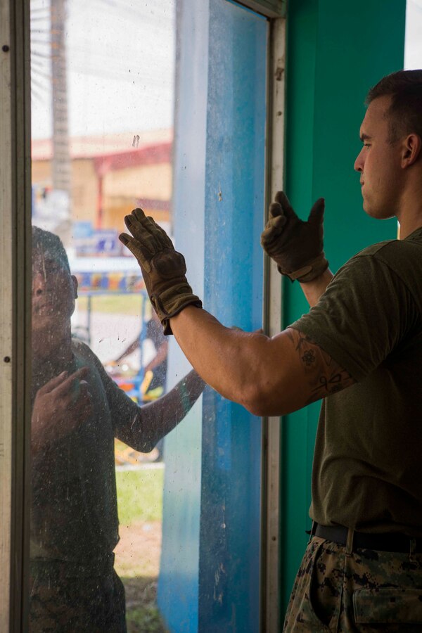 U.S. Marine Corps Sgt. Garrett Burn, a combat engineer, and Lance Cpl. Charles Alford, a heavy equipment operator, from 8th Engineer Support Battalion, 2nd Marine Logistics Group remove a piece of glass in order to reapply a water proofing seal around the edges of the window pane. The Guatemalan Brigada de Infanteria de Marina (BIM) engineers along with their U.S. counterparts help renovate the Biblioteca Municipal Corporacion 74-78 as part of a humanitarian engineering project in Puerto Barrios, Guatemala, Aug. 14, 2014. The Marines and Sailors are helping to remodel buildings in support of Southern Partnership Station 2014, a combined joint exercise focused on subject matter expert exchanges with partner nations and security forces as well as military to military engagements and community relations projects in Central America. (U.S.  Marine Corps photo by Lance Cpl. Chloe Nelson, 2D MAR DIV Combat Camera/ Released)