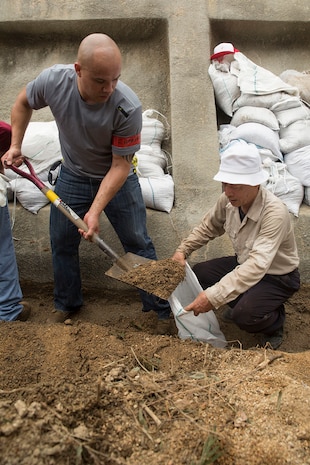 Staff Sgt. Juan Ramirez, a volunteer from Marine Corps Air Station Iwakuni, Japan, and a Japanese local volunteer fill sandbags while cleaning up damage done by Typhoon Halong in Sunayamacho, Iwakuni, August 14, 2014. Typhoon Halong peaked as a Category 5 Super Typhoon, causing landslides, mudslides and heavy flooding, resulting in deaths, injuries, and damage throughout Japan.