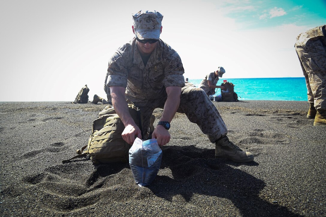 A Marine with the 11th Marine Expeditionary Unit collects volcanic debris on his way toward Mount Suribachi, Iwo To, Japan as part of the MEU’s WESTPAC 14-2 deployment Aug. 16, 2014. The 11th MEU and Makin Island Amphibious Ready Group are deployed to the U.S. 7th Fleet area of operations as a sea-based, expeditionary crisis response force capable of conducting amphibious missions across the full range of military operations.  (U.S. Marine Corps photo by Lance Cpl. Laura Raga/Released)