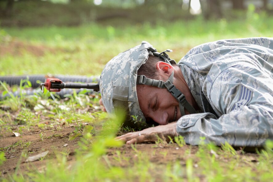 Staff Sgt. Daniel Knowlton, 374th Civil Engineer Squadron, grimaces while low crawling through dirt during the 374 CES Prime Beef training day at Yokota Air Base, Japan on Aug. 21, 2014. The training is required on a monthly basis and ranges from PowerPoint slides to field exercises. (U.S. Air Force photo by Senior Airman Michael Washburn/released)  