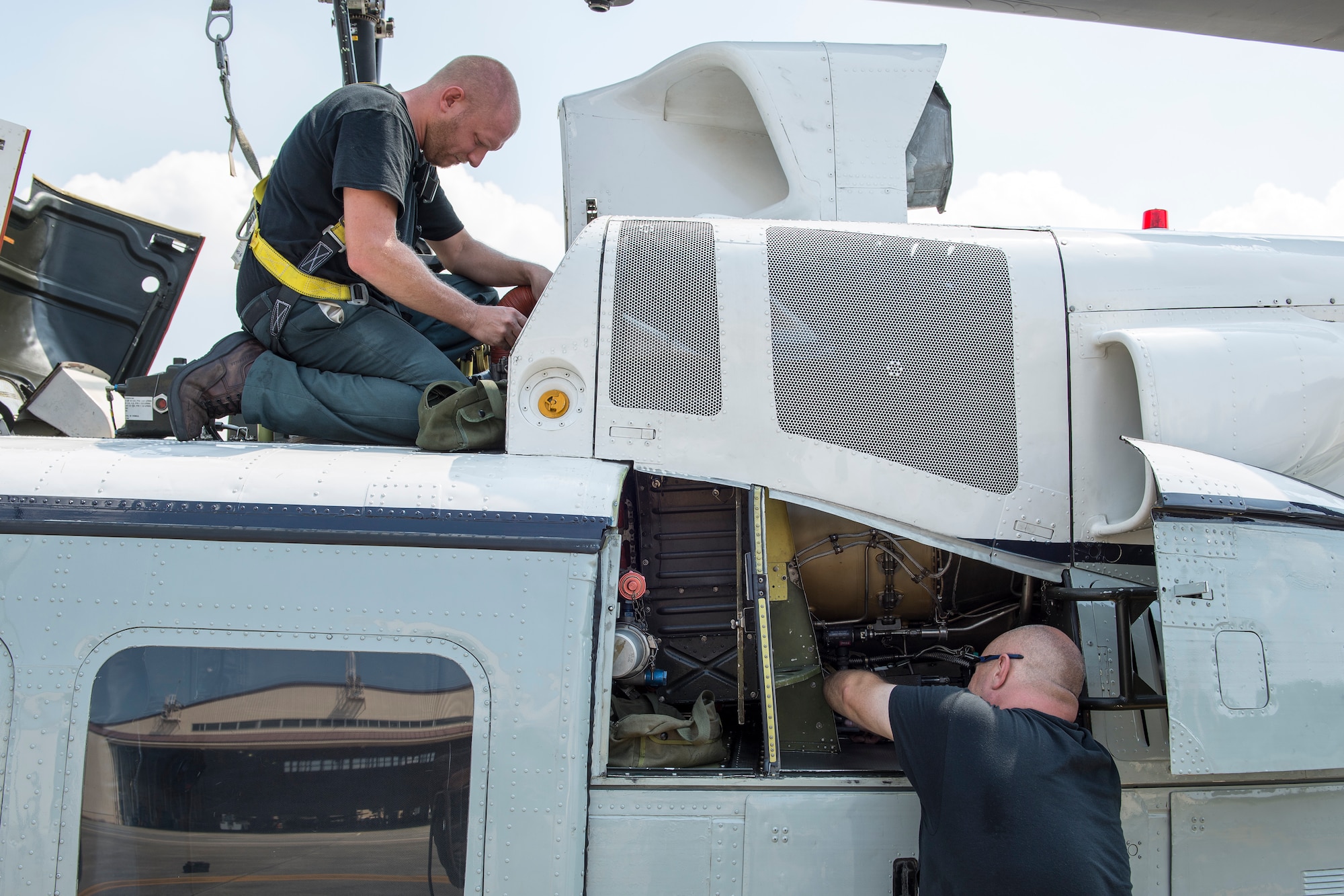 (Top to down) Joshua Keller and Todd Hanson, 374th Maintenance Group contractors, maintain a UH-1N Iroquois at Yokota Air Base, Japan on Aug. 20, 2014. The UH-1N maintainers from the 374th MXG ensure the helicopters are prepared to respond to any type of mission—day or night. (U.S. Air Force photo by Osakabe Yasuo/Released)
