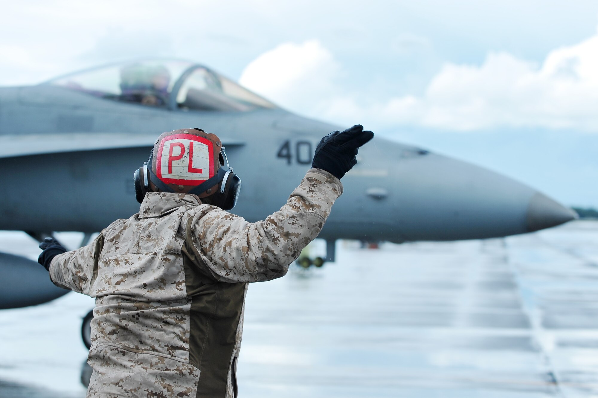A U.S. Marine Corps maintainer assigned to the Marine Fighter Attack Squadron 323, Marine Corps Air Station Miramar, Calif.,  marshals a F/A-18C Hornet during RED FLAG-Alaska 14-3 Aug. 18, 2014, Eielson Air Force Base, Alaska. In its fighter mode, the F/A-18 is used primarily as a fighter escort and for fleet air defense. (U.S. Air Force photo by Staff Sgt. Jim Araos/Released)