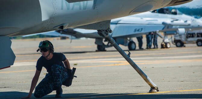 A Navy EA-18G Growler maintainer completes a check before take-off Aug. 6, 2014, at Naval Air Station Whidbey Island, Wash. The Navy and Air Force have the added benefit of understanding Navy terms and are able to translate to their Air Force partners. (U.S. Air Force photo by Airman 1st Class Malissa Lott) 

