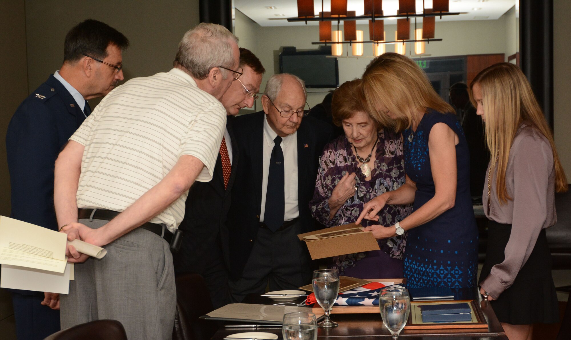 Helaine Blizzard, second cousin of Capt. John Perrin, second from right, shows a momento to the presentation attendees June 26, 2014, in Dallas. Perrin steered his failing aircraft away from the populated areas of Stafford and Creswell, England, resulting in the loss of his life. (Photo by Staff Sgt. Samantha Mathison)