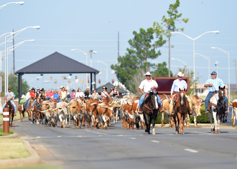 ALTUS AIR FORCE BASE, Okla. – Ranchers from the Great Plains Stampede Rodeo guide a herd of longhorn cattle onto Altus AFB during the 16th Annual Base Cattle Drive, Aug. 21, 2014. The event is a tradition that started Aug. 26, 1999 when 15 riders drove a herd of longhorn cattle through the streets of Altus AFB. (U.S. Air Force photo by Senior Airman Levin Boland/Released)