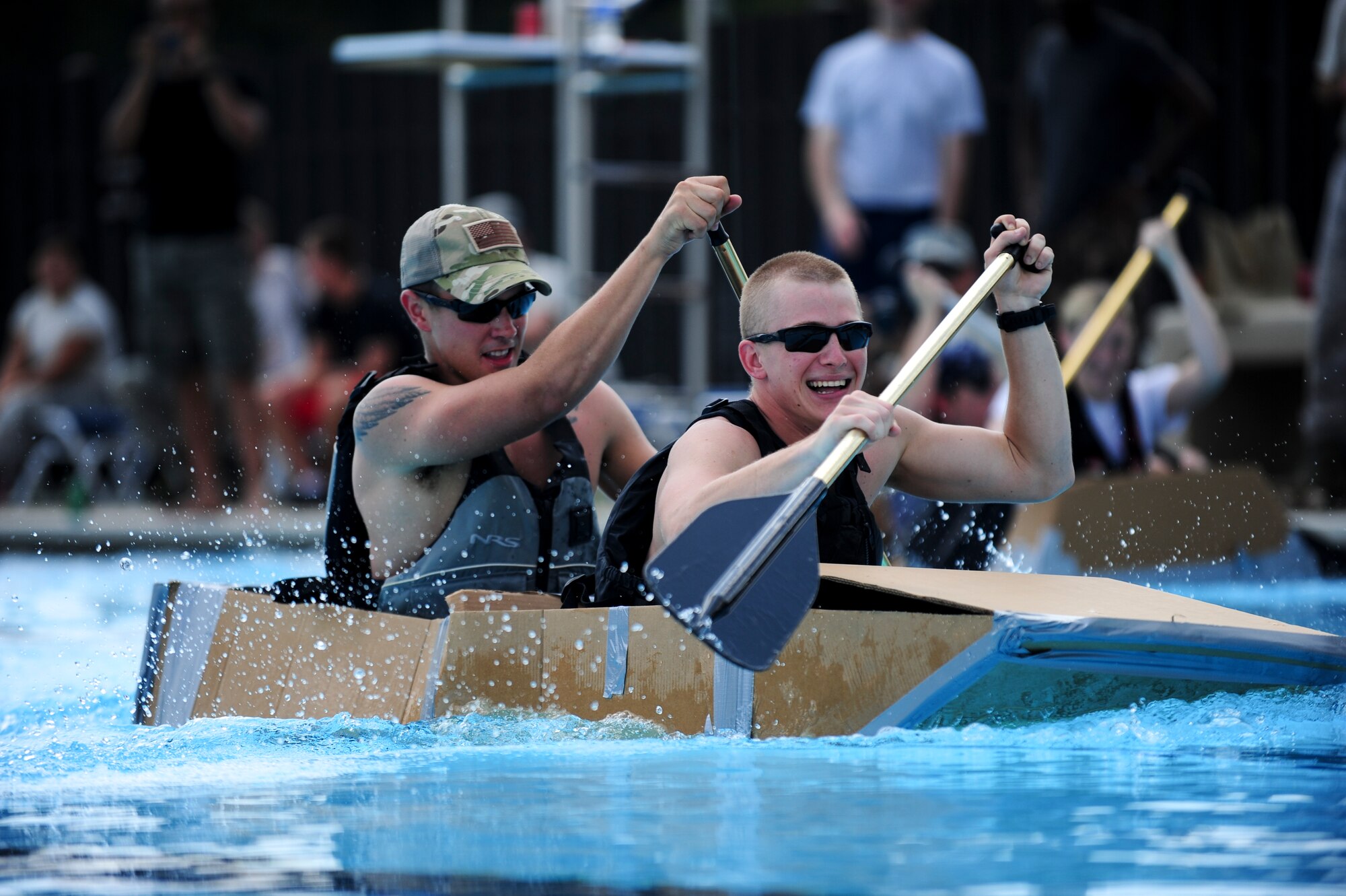 Airmen 1st Class Michael Long (front) and Domenic Martino, 4th Civil Engineer Squadron explosive ordnance disposal technicians, row across the base pool during the 4th Fighter Wing Build-a-Boat Competition on Aug. 20, 2014, at Seymour Johnson Air Force Base, North Carolina.  The EOD team won the competition by rowing their man-made boat the length of the pool in 53.28 seconds. (U.S. Air Force photo/Airman 1st Class Brittain Crolley)
