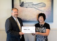 Beale Military Liaison Committee member Janice Nall (right) receives a $15,000 check from a Northrop Grumman representative during a ceremony held at Beale Air Force Base, Calif., Aug. 14, 2014. The funds were donated in honor of Operation Warm Heart, which is a program that funds quality of life projects for Airmen and their families. (U.S. Air Force photo by John Schwab/Released)