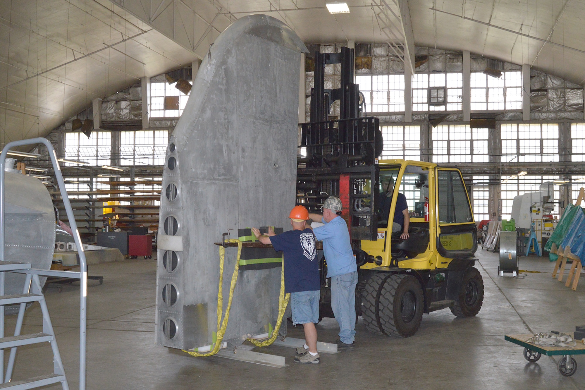 DAYTON, Ohio (08/2014) -- (From left to right) Restoration Specialists Duane Jones, Roger Brigner, and Chad Vanhook prepare to attach the vertical stabilizer to the fuselage of the B-17F "Memphis Belle"® at the museum's restoration hangar. Plans call for the aircraft to be placed on display in the museum's World War II Gallery in spring 2018. (U.S. Air Force photo)