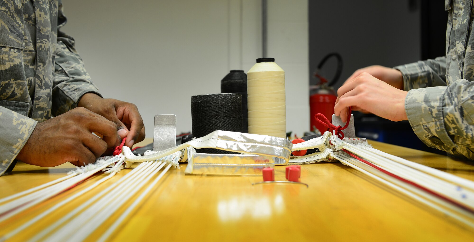 Airmen 1st Class Alixandra Druckenmiller and Darien Hackett, 31st Operations Support Squadron aircrew flight equipment technicians, prepare an ACES II parachute, Aug. 19, 2014, at Aviano Air Base, Italy. The 11-Airmen flight attached to the 510th Fighter Squadron is broken up into different shops. One prepares pilots’ helmets, head-up displays, suits, radios and harnesses and the other shop packs parachutes, life preservers and survival kits. (U.S. Air Force photo/Senior Airman Matthew Lotz)