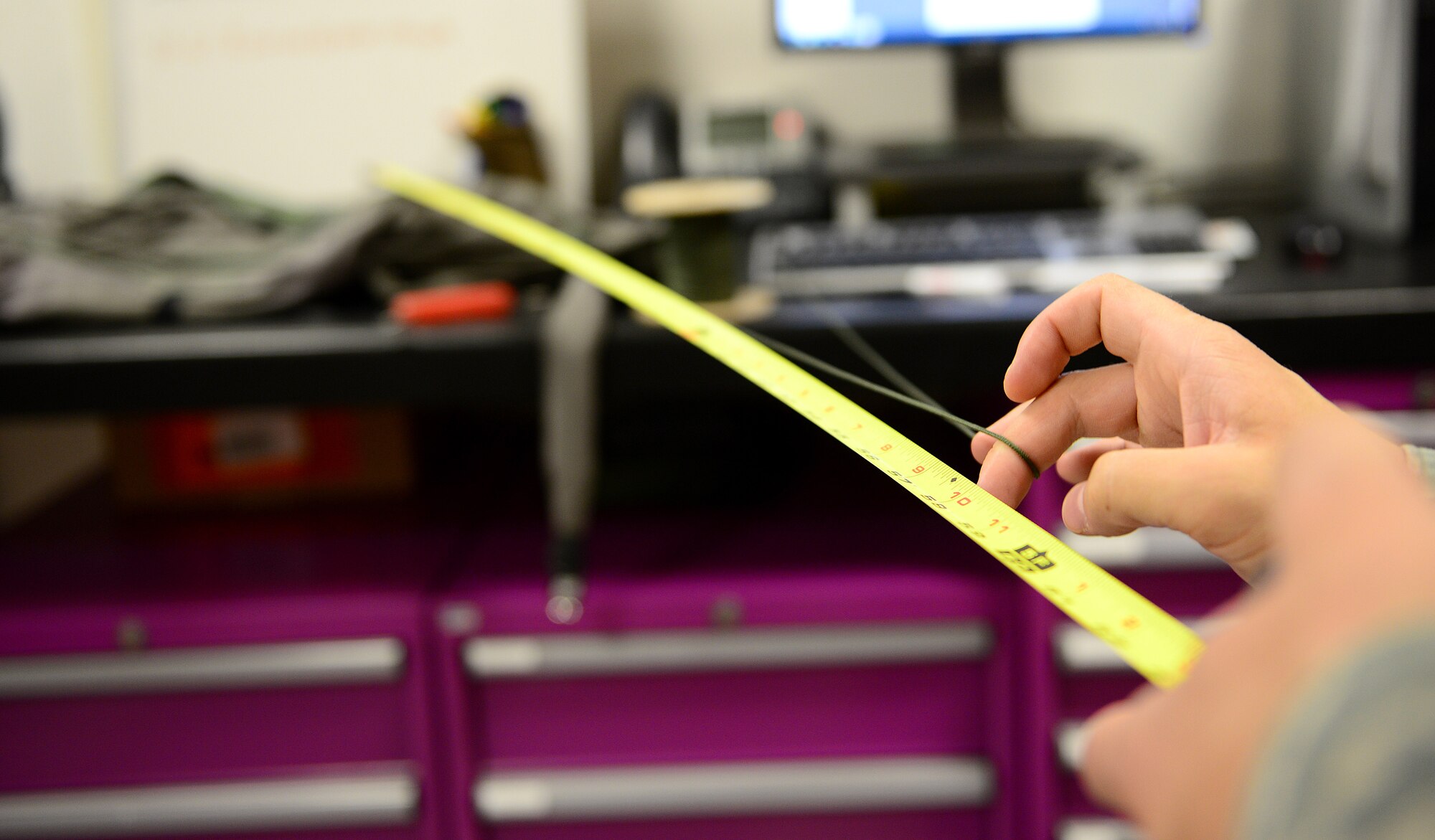 Senior Airman Matthew Brillion, 31st Operations Support Squadron aircrew flight equipment technician, measures a 100 pound cord lanyard for a pilot’s riser cutter knife, Aug. 19, 2014, at Aviano Air Base, Italy. The AFE Airmen store the knife in a pilot’s G-suit, that is located to make it easy for them to reach down, grab the knife and cut any lines in the parachute that are tangled and could cause them to spin out of control. (U.S. Air Force photo/Senior Airman Matthew Lotz)