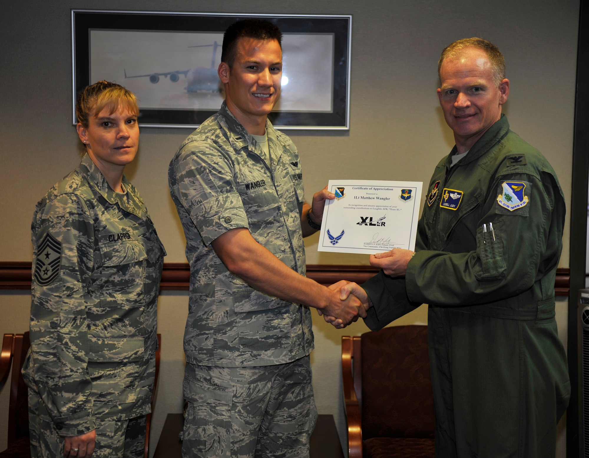First Lieutenant Matthew Wangler, center, 47th Flying Training Wing chief of command post poses with Col. Darrell Judy, right, 47th FTW vice commander, and Chief Master Sgt. Teresa Clapper, left, 47th FTW command chief, after being presented the XLer of the week award here Aug 20, 2014. The XLer is a weekly award chosen by wing leadership and given to those who consistently make outstanding contributions to their unit and Laughlin. (U.S. Air Force photo by Staff Sgt. Nathan Maysonet)(Released)