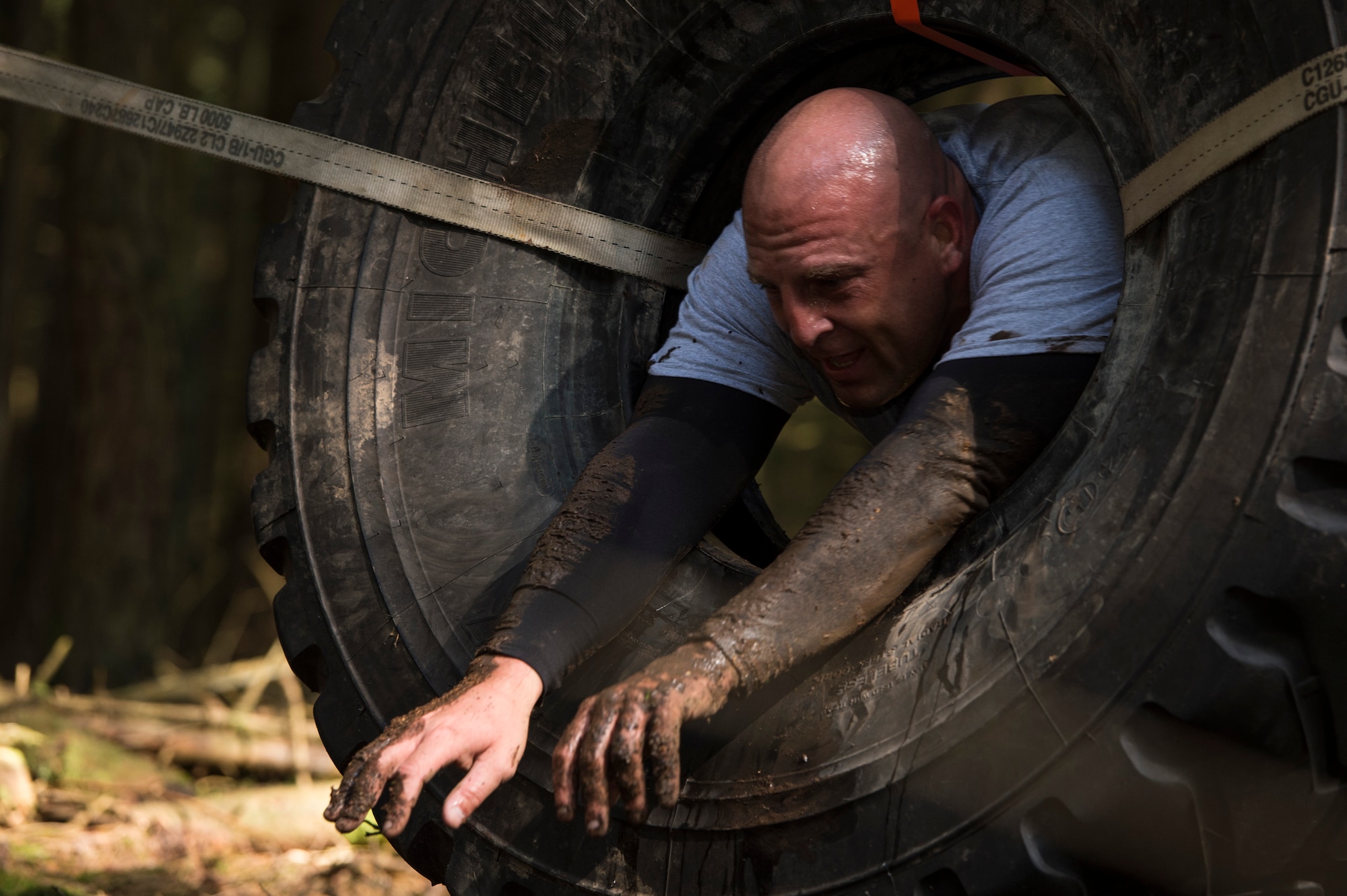 Senior Master Sgt. Jason Theriault, 52nd Civil Engineer Squadron deputy fire chief, climbs through a tire during the second annual Tier II 5K Mud Run Aug. 20, 2014, at Spangdahlem Air Base, Germany. All the proceeds from the event went to the Fisher House in Landstuhl. (U.S. Air Force photo by Staff Sgt. Christopher Ruano/Released)