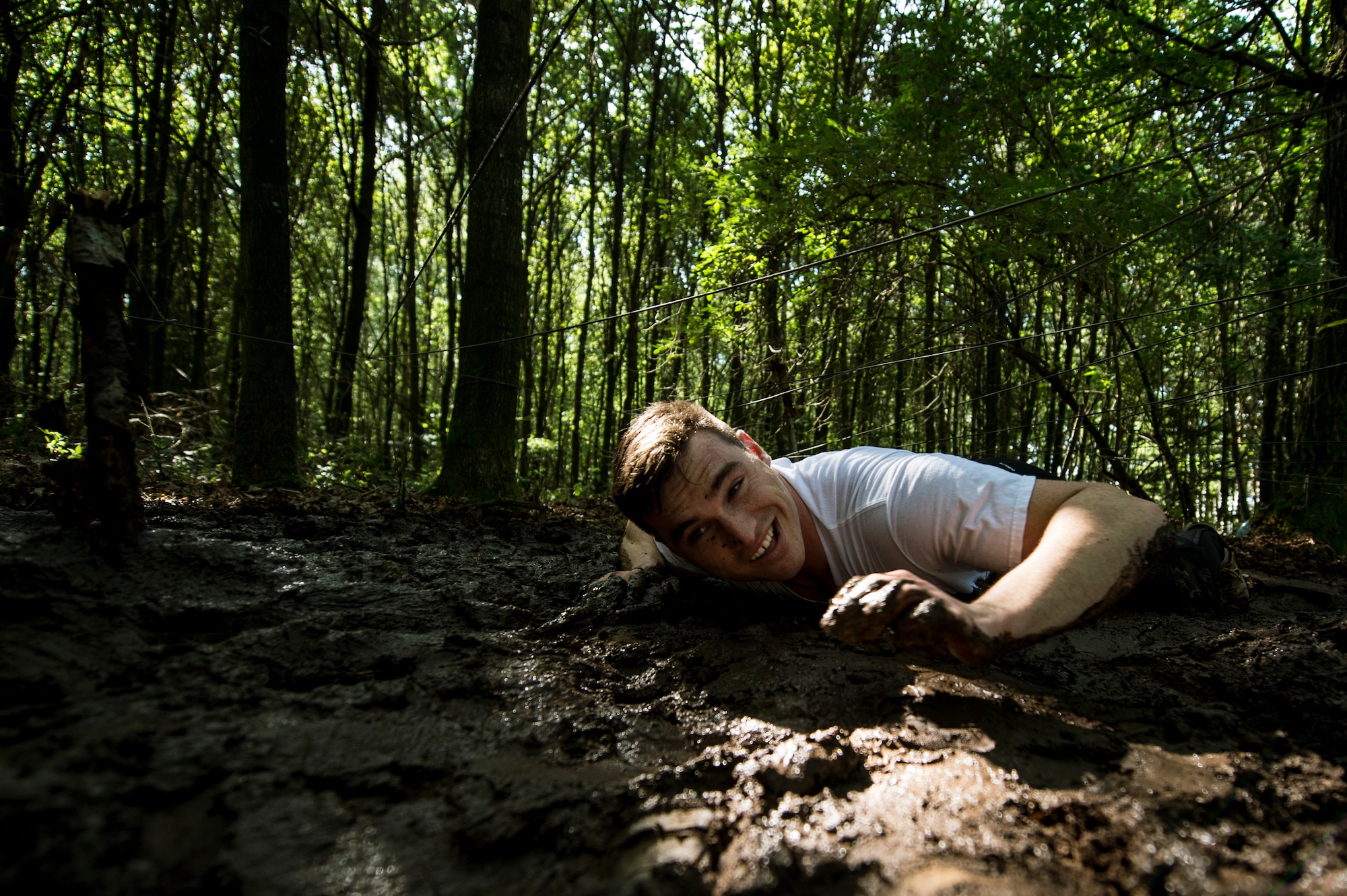U.S. Air Force Staff Sgt. Daniel Felice, a 52nd Component Maintenance Squadron electronic warfare systems team leader from San Diego, low crawls in the mud during the second annual Tier II 5K Mud Run Aug. 20, 2014, at Spangdahlem Air Base, Germany. Low crawling was one of the many obstacles that Airmen endured. (U.S. Air Force photo by Senior Airman Rusty Frank/Released)