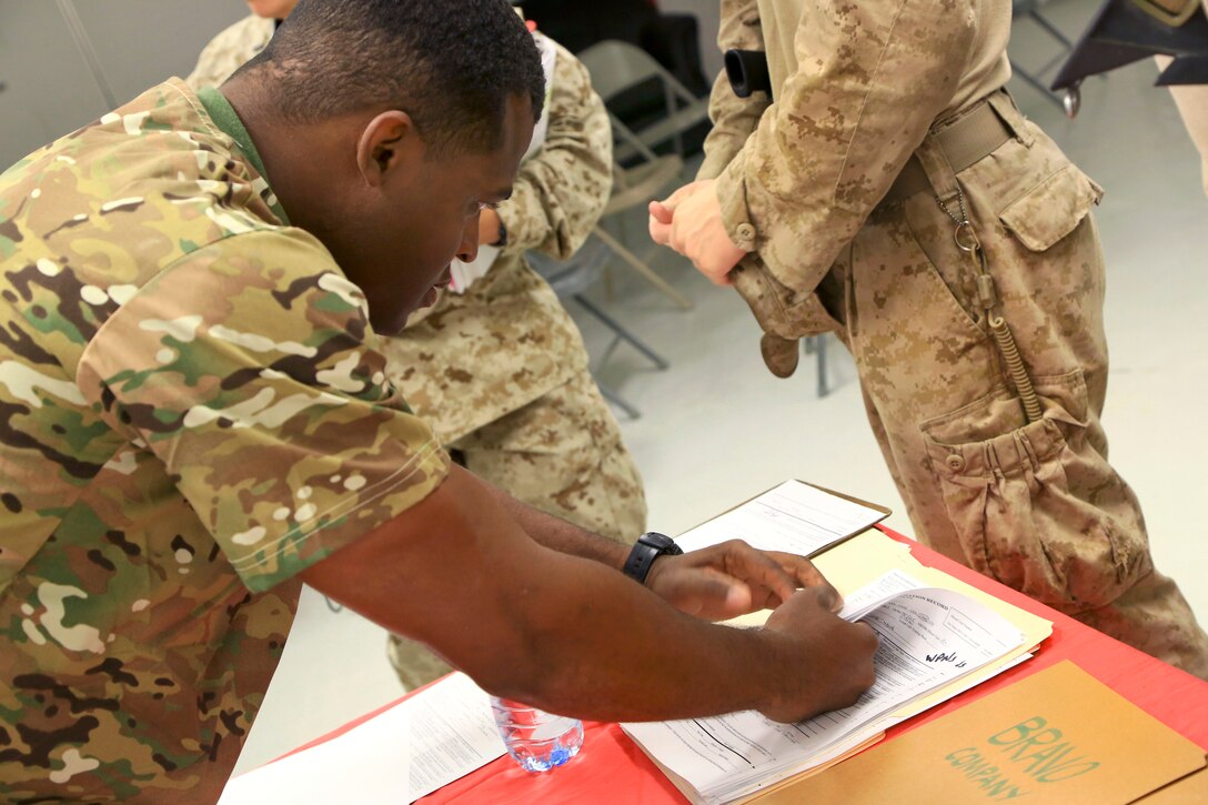 U.S. Navy Petty Officer 2nd Class Kowalsky Lucien assits a U.S. Marine on the correct way to fill out required paperwork during a walking blood bank on Camp Leatherneck, Helmand province, Afghanistan, Aug. 14, 2014. Lucien is a hospital corpsman assigned to Combat Logistics Battalion 1.
