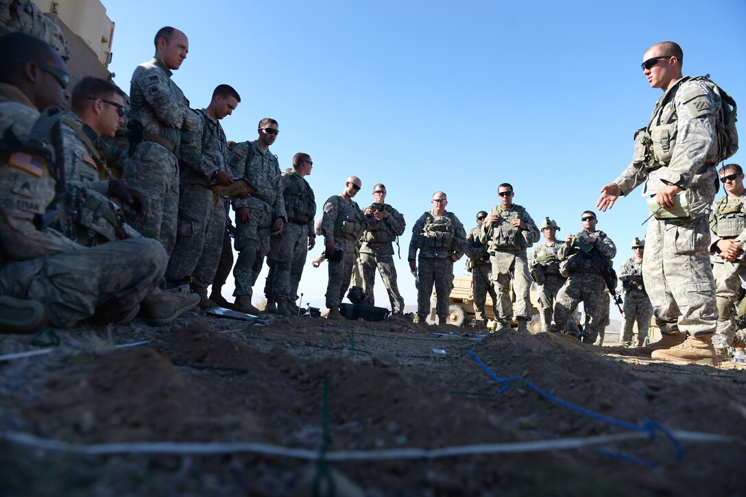 Soldiers listen to a pre-mission briefing during Decisive Action Rotation 14-09 on the National Training Center in Fort Irwin, Calif., Aug. 9, 2014. Decisive action rotations prepare soldiers for a wide array of potential adversaries including guerrilla, insurgent, criminal and conventional forces. The soldiers are assigned to the 3rd Infantry Division's 1st Armored Brigade Combat Team. 