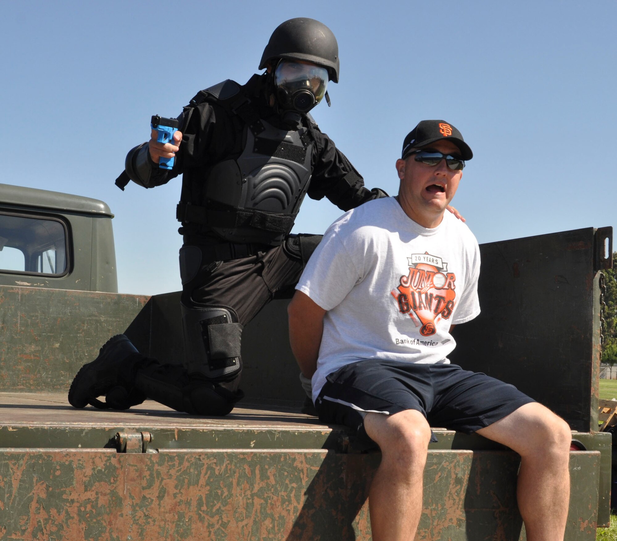 Master Sgt. Paul Ragan is held captive by a member of the Solano County Sherriff’s Department, who was dressed up as a bad guy, Aug. 15, 2014, at Solano Community College in Fairfield, Calif. This scenario was created for D’Marrion Otten, a Make-a-Wish foundation wish recipient, as part of being a superhero for a day. Ragan is D’Marrion’s baseball coach and the 60th Civil Engineer Squadron NCO in charge (U.S. Air Force photo/Airman 1st Class Amber Carter)