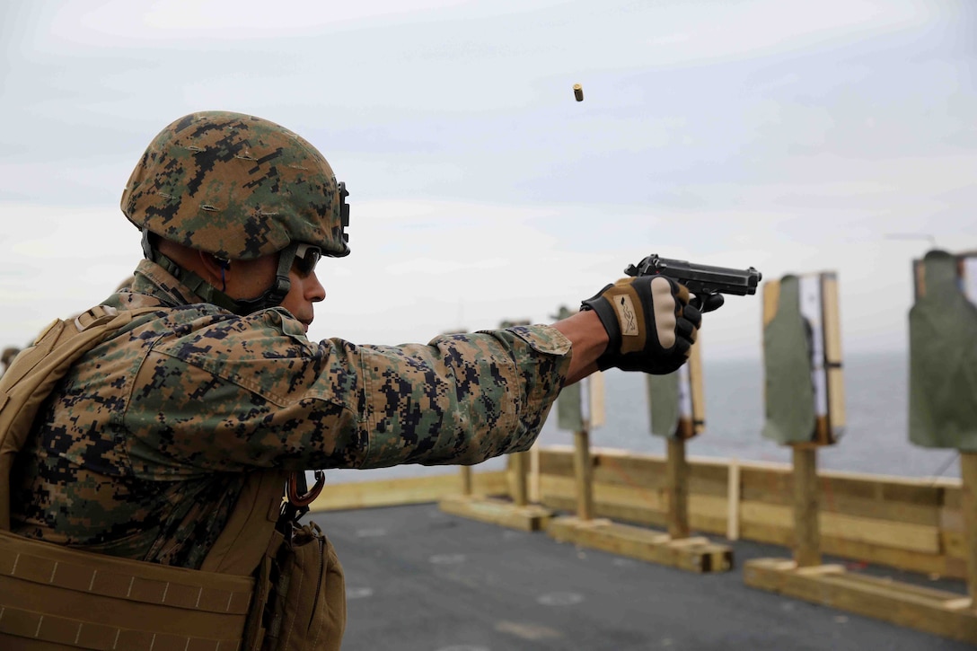 Petty Officer 3rd Class James Johnson, a U.S. Navy hospital corpsman with Special Purpose Marine Air Ground Task Force South, of New Orleans, fires at his target during a live-fire exercise on the flight deck of the future amphibious assault ship USS America, Aug. 15, 2014. The purpose of the exercise was to refresh the Marines on weapons handling and marksmanship with the M4 service rifle and M9 service pistol. 