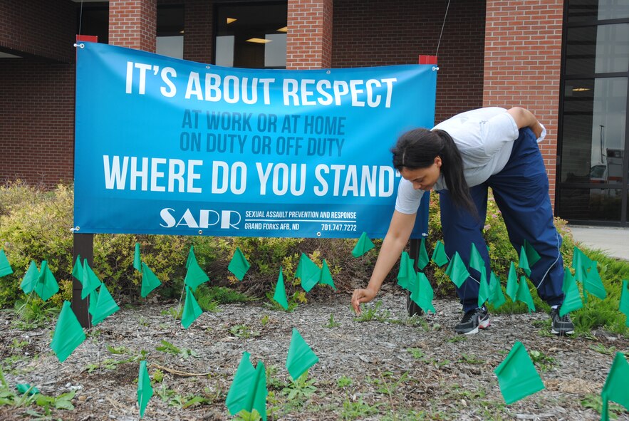 Senior Airman Vernita Murray, 319th Medical Group, plants a green flag into the ground in support of Sexaul Assault Prevention and Repsonse program on Aug. 21, 2014, at grounds of the fitness center on Grand Forks Air Force Base, N.D.The planting of the small green flags was done as part of the optional activities available for military members and their families during Summer Bash 2014. The bash is designed to boost base morale and increase esprit de corps. (U.S. Air Force photo collage/Staff Sgt. Luis Loza Gutierrez) 

