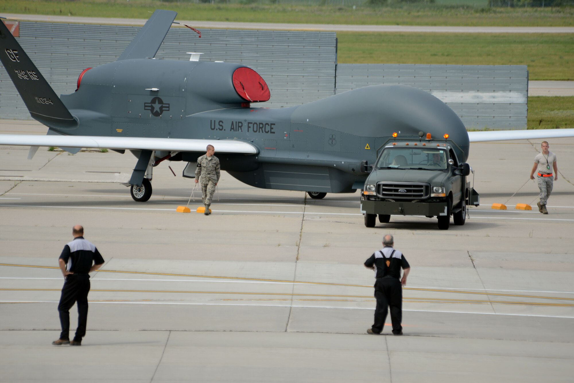 Members from the 319th Operations Support Squadron airfield management section along with Airmen from the 69th Reconnaissance Group carefully move an RQ-4 Global Hawk Block 40 into position for a large scale group photo scheduled to take place Aug. 20, 2014, on the flightline on Grand Forks Air Force Base, N.D. The first ever Unmanned Aircraft Systems Airspace Integration Test in the U.S., which took place Aug. 4-22, 2014, at Grand Forks AFB, included multiple unmanned aerial vehicles such as the Global Hawk. (U.S. Air Force photo/Senior Master Sgt. David Lipp)