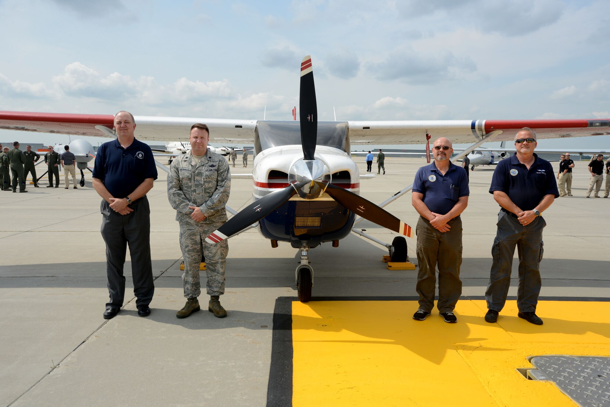 Standing by a CAP Cessna, members from the North Dakota Civil Air Patrol pose for a group photo on the flightline of Grand Forks Air Force Base, N.D., on Aug. 20, 2014. The CAP Airmen from the particiapted in the first ever Unmanned Aircraft Systems Airspace Integration Test in the U.S., which took place Aug. 4-22, 2014, at Grand Forks AFB. (U.S. Air Force photo/Senior Master Sgt. David Lipp)