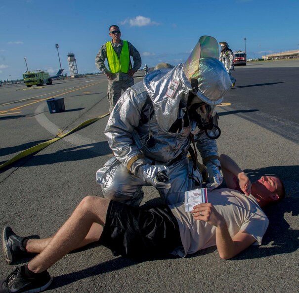 A member of the 647th Civil Engineer Squadron Fire Department checks on a simulated injured patient during a major accident response exercise on the Joint Base Pearl Harbor-Hickam flightline Aug. 21, 2014. During the MARE, Airmen were moulaged and positioned near a simulated crash site to test the emergency response of military and civilian first responders. The 15th Wing partnered with the 154th Wing, Joint Base and first responders from the local community to conduct the exercise in preparation for the upcoming airshow Sept. 27-28. (U.S. Air Force photo by Tech. Sgt. Terri Paden)