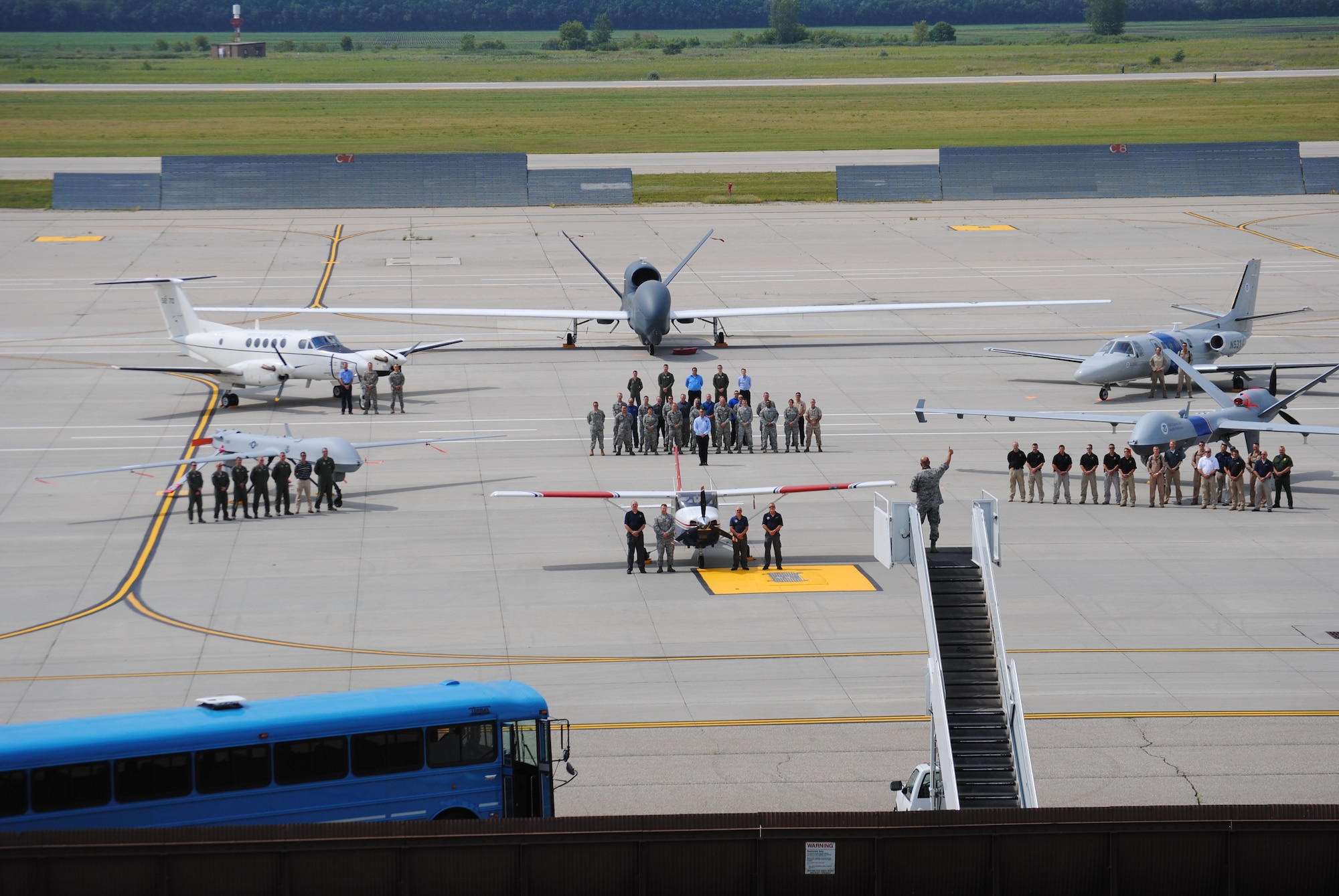 Atop a mobile stairs vehicle, Senior Master Sgt. David Lipp, signals he got the right shot by giving a thumb's up to members of multiple federal organizations posing for a group photo featuring both manned and unmanned aircraft from their respective organizations, Aug. 20, 2014, on the flightline of Grand Forks Air Force Base, N.D. The superintendent/photojournalist from the North Dakota Air National Guard’s 119th Wing in Fargo, N.D., was asked to take the group photo as a way of commemorating the historic achievement of the first ever Unmanned Aircraft Systems Airspace Integration Joint Test that took place Aug. 4-22, 2014. The Happy Hooligans from the 119th Wing, Detachment 1, a geographically separated unit on Grand Forks AFB, took part of the joint test. (U.S. Air Force photo/Staff Sgt. Luis Loza Gutierrez)