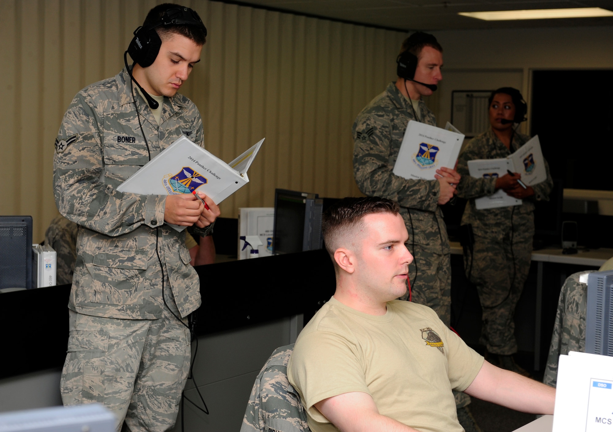 Airman 1st Class Troy Boner, 460th Operations Support Squadron space operator, looks over the shoulder of Senior Airman Eric Richards, 2nd Space Warning Squadron space operator, during the 460th Operations Group Panther Challenge Aug. 5, 2014, on Buckley Air Force Base, Colo. The challenge, held Aug. 4-13, was developed to provide members of Team Buckley an opportunity to improve their skills and expand their job knowledge in a competitive setting. Participants in the challenge included the 2nd and 8th Space Warning Squadrons, 460th Security Forces Squadron, and 460th Medical Group. (U.S. Air Force photo by Airman 1st Class Samantha Saulsbury/Released)