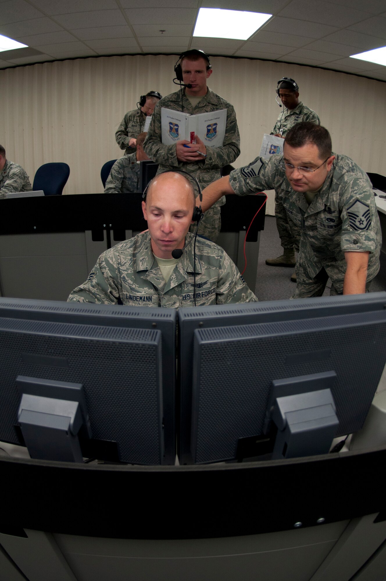 Senior Airman Jeremy Lindemann, 8th Space Warning Squadron, seated, and Master Sgt. Michael Taylor, right, respond to a simulated event while being evaluated by members of the 460th Operations Support Squadron during the 460th Operations Group Panther Challenge Aug. 4, 2014, on Buckley Air Force Base, Colo. The challenge, held Aug. 4-13, was developed to provide members of Team Buckley an opportunity to improve their skills and expand their job knowledge in a competitive setting. Participants in the challenge included the 2nd and 8th Space Warning Squadrons, 460th Security Forces Squadron, and 460th Medical Group. (U.S. Air Force photo by Tech. Sgt. Kali L. Gradishar/Released)