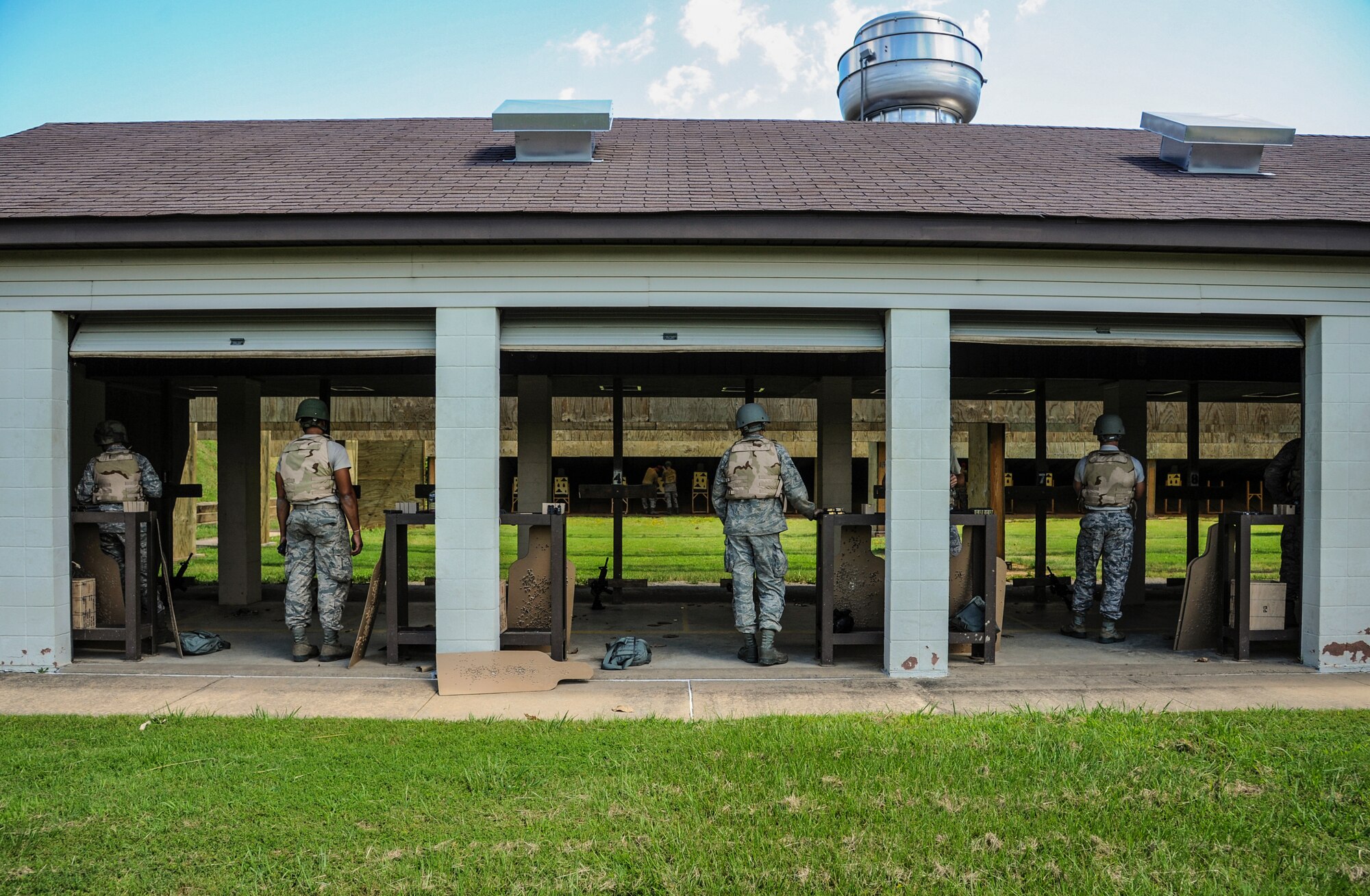 A group of Airmen from the 19th Airlift Wing watch a combat arms training and maintenance instructor analyze a target to determine their firing accuracy Aug. 12, 2014, at Little Rock Air Force Base, Ark. CATM instructors teach the proper use of a variety of weapons, including the M4 assault rifle, M9 pistol and the M107 sniper rifle. (U.S. Air Force photo by Airman 1st Class Harry Brexel) 