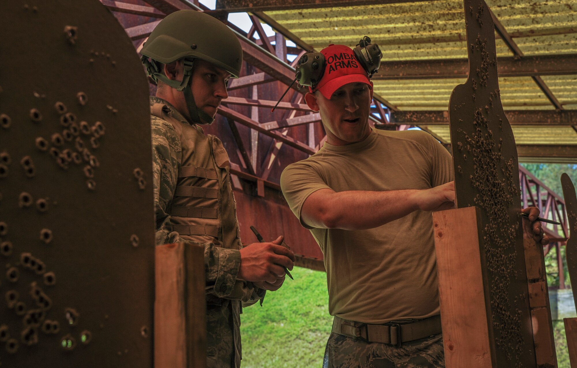 Airman 1st Class Christopher McEwen, a 19th Aircraft Maintenance Squadron crew chief (left), listens to weapon sight adjustment instruction from Tech. Sgt. John Kinsella, 19th Security Forces combat arms training and maintenance noncommissioned officer in charge, Aug. 12, 2014, at Little Rock Air Force Base, Ark. Kinsella reviewed McEwen's target in order to assess if the M4 assault rifle qualifications were met. (U.S. Air Force photo by Airman 1st Class Harry Brexel)