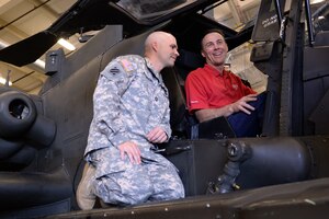 U.S. Army Sgt. 1st Class Daniel Addison, B Company, 1st Battalion, 210th Aviation Regiment, instructor and senior  avionics training management noncommissioned officer, shows Kevin Harvick, NASCAR driver, the inner workings of a modified trainer AH-64 Apache helicopter during a tour of the 128th Aviation Brigade at Fort Eustis, Va., Aug. 20, 2014. Harvick toured Fort Eustis to learn about the installation’s different missions, and to thank Soldiers for their service. (U.S. Air Force photo by Staff Sgt. Teresa J.C. Aber/Released)