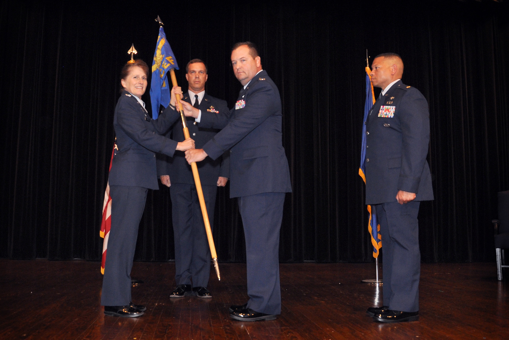 Col. James Clutter passes the guidon to Col. Karen Magnus, 916th Mission Support Group commander. Clutter relinquished command of the 916th Civil Engineer Flight to Maj. Oliver George during a ceremony held in the Seymour Johnson Air Force Base theatre, Aug. 2014. (U.S. Air Force photo by Staff Sgt. Alan Abernethy)