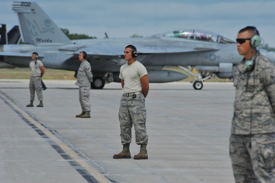 A U.S. Navy F-18 taxis the flight line of the Alpena Combat Readiness Training Center in Alpena, Michigan while U.S. Air Force crew chiefs from the 180th Fighter Wing standby to direct F-16 Fighting Falcons, Aug. 21, 2014. The 180th Fighter Wing deployed to the CRTC to participate Operation Northern Strike, a joint exercise led by the National Guard that demonstrates the combined power of the air and ground forces. (Air National Guard photo by Staff Sgt. Amber Williams/Released)