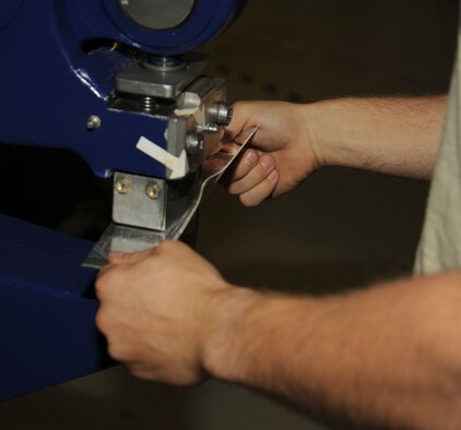 Staff Sgt. Casey Durham uses a shrink and stretch machine to bend the extrusion to the final contour size at Fairchild Air Force Base, Washington, Aug. 20, 2014. The machine is used to bend metal to the correct size by shrinking it or stretching it. Part of Durham’s day- to-day work is doing a full inspection of the tanker for preventative maintenance, evaluate damage and corrosion on the aircraft and paint and place decals. Durham is an aircraft structural craftsman from the 92nd Maintenance Squadron. (U.S. Air Force photo/Staff Sgt. Samantha Krolikowski)