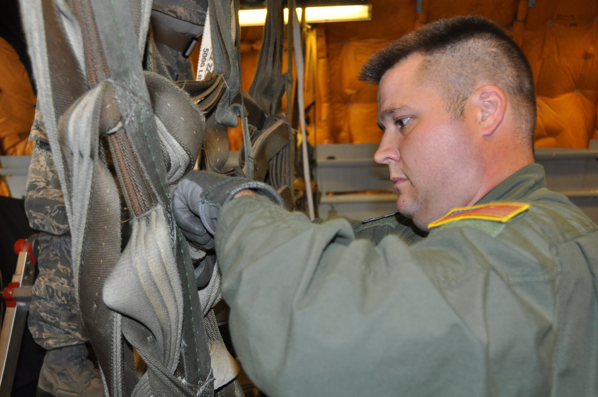 Tech Sgt. Todd Dallman, 76th Air Refueling Squadron boom operator, fastens the straps of a cargo barrier net to secure 27700 lbs. worth of cargo aboard a KC-10 aircraft prior to departure to Ramstein Air Base, Germany July 25. The aircraft supports up to 170,000 lbs. of cargo and can be configured to support medical evacuations, large passenger loads and/or heavy cargo pallets (U.S. Air Force photo/Senior Airman Chelsea Smith).