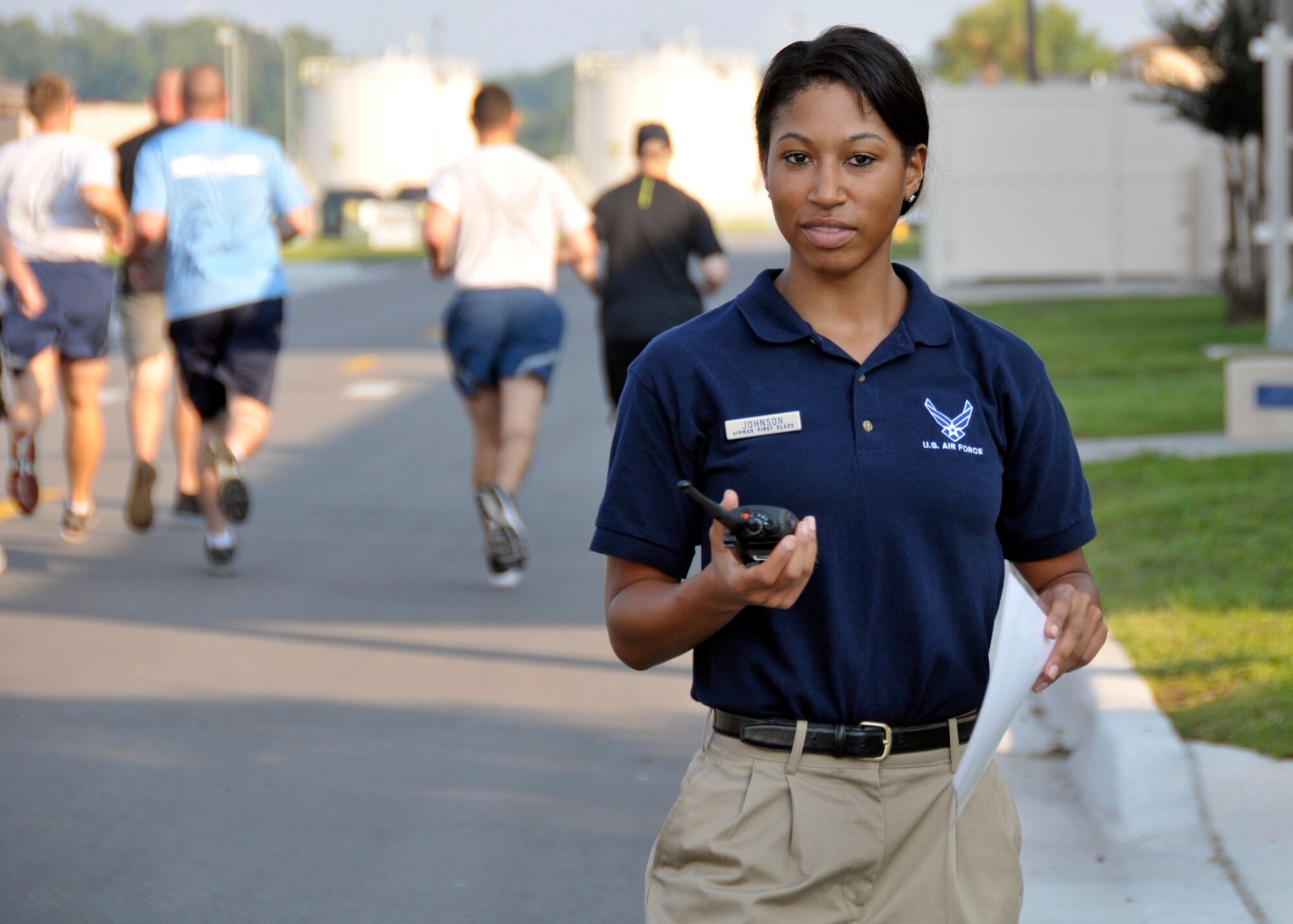 U.S. Air Force Airman 1st Class Ishimine Johnson announces the beginning of the running portion for a physical training (PT) test over a radio to fellow PT leaders at the 125th Fighter Wing, Jacksonville International Airport, Jacksonville Florida., Aug. 17, 2014. Johnson spends her time off from the Air National Guard training for and competing in bodybuilding competitions. (U.S. Air Force photo by Staff Sgt. Troy Anderson/RELEASED)