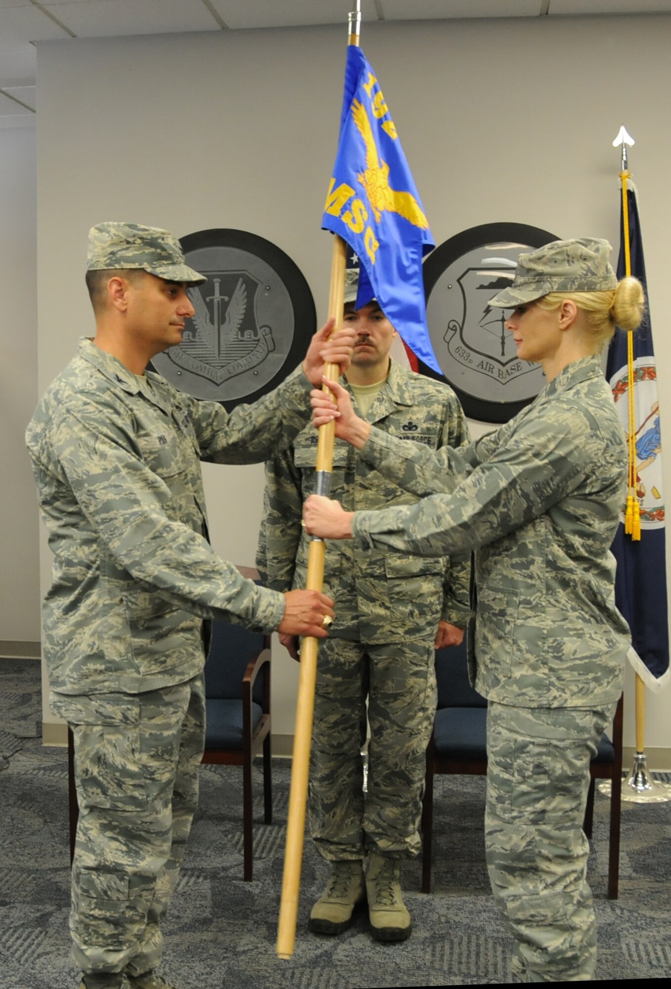 U.S. Air Force Col. Jeffrey Ryan (left), 192nd Mission Support Group Commander, presents Lt. Col. Mary Decker with the organizational colors to signify her taking command from Lt. Col. Toni Lord during a traditional change of command ceremony held at Langley Air Force Base, Va., July 12, 2014.  (U.S. Air National Guard photo by Master Sgt. Carlos J. Claudio/Released)