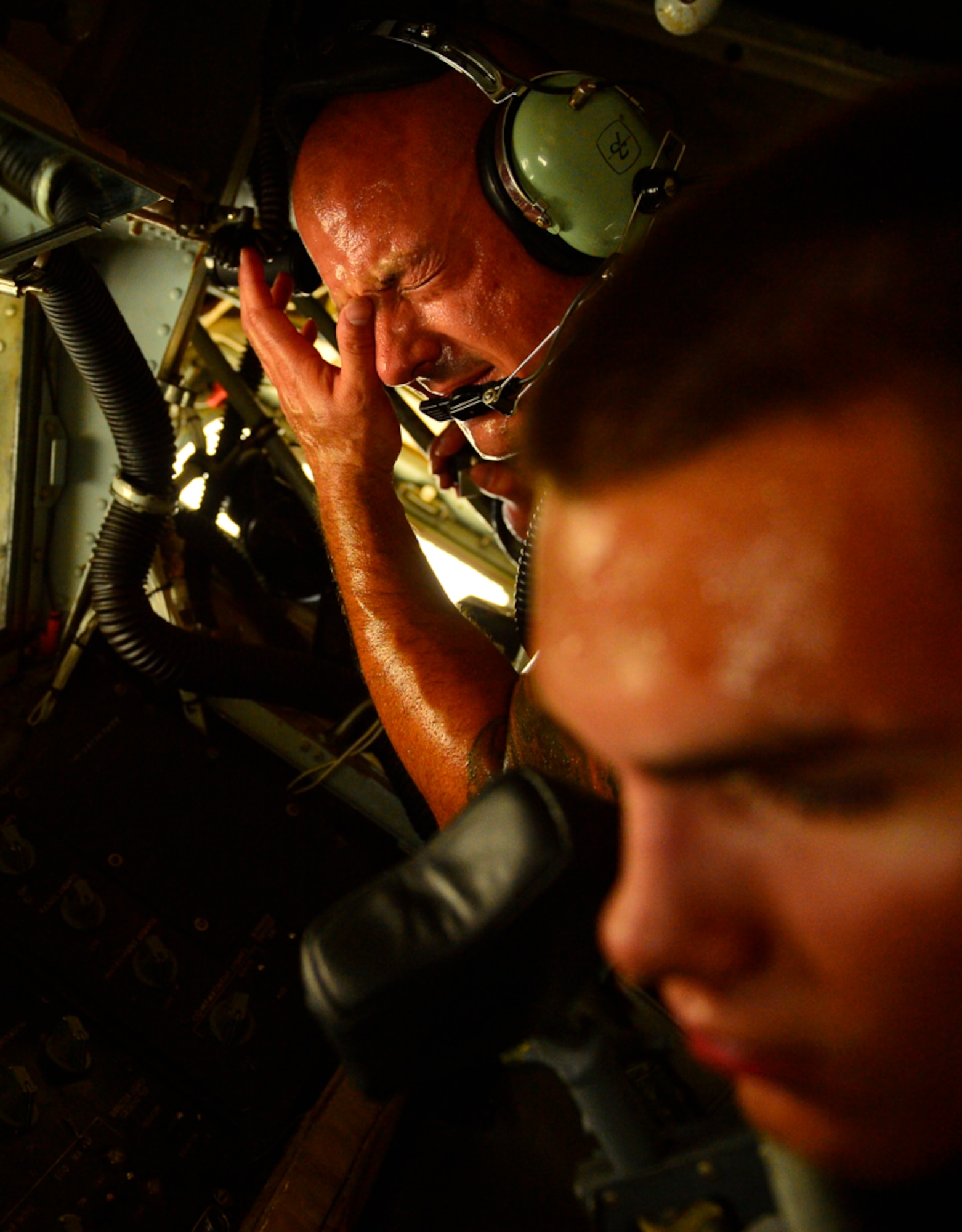 Tech Sgt. Ryan Riley wipes sweat from his brow while he and Airman 1st Class Connor Sweeney, 340th Expeditionary Aircraft Maintenance Unit hydraulic systems craftsman, work together to adjust the aircrafts boom pod shaft, Aug. 5, 2014, Al Udeid Air Base, Qatar. Airmen who perform maintenance on the flight line here endure stifling heat, sand and wind to keep air refueling aircraft and a multitude of other airframes constantly taking off and landing day and night.  (U.S. Air Force photo by Staff Sgt. Vernon Young Jr.)