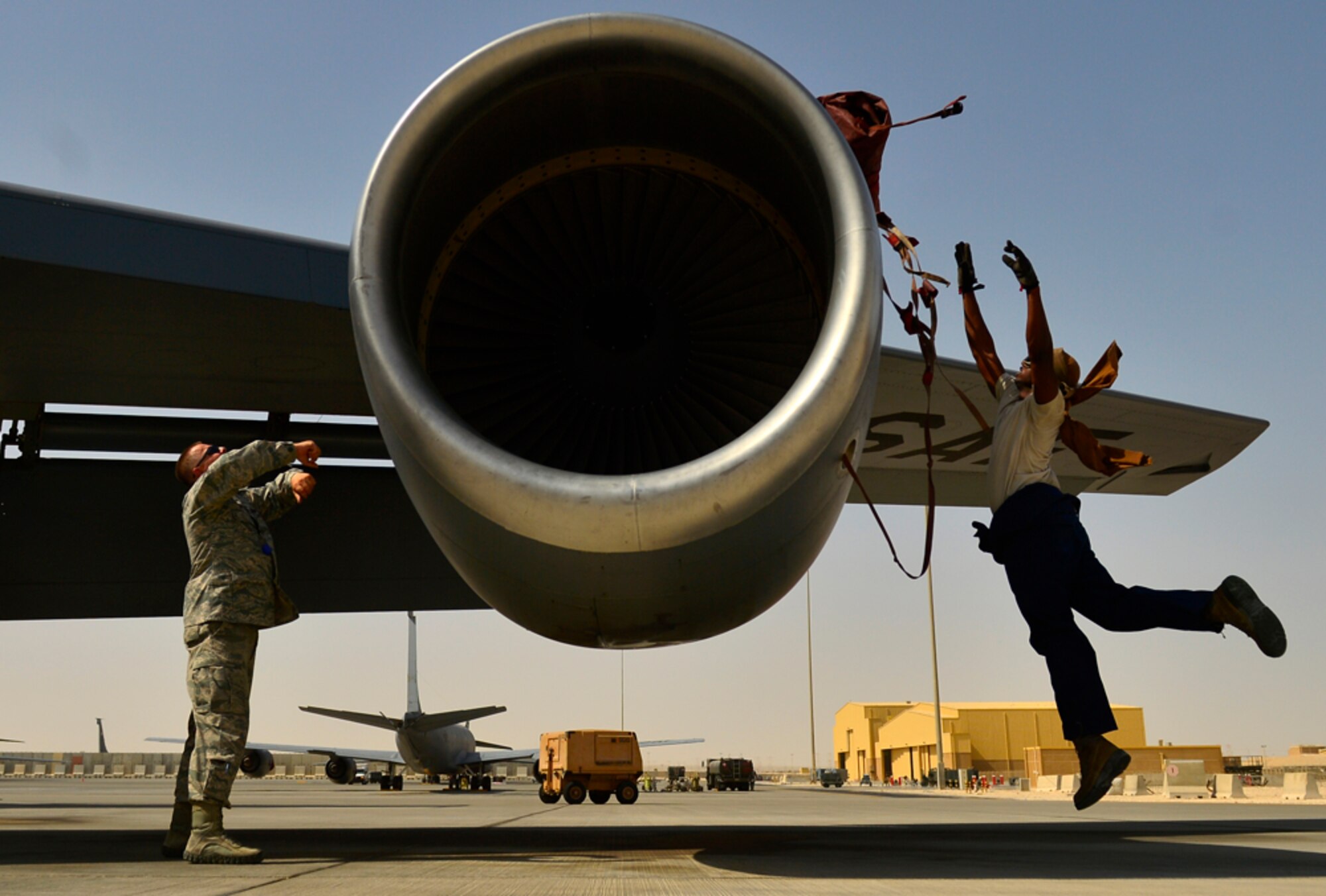 Senior Master Sgt. Ernie Goethe, 340th Expeditionary Aircraft Maintenance unit senior, assists Senior Airman Darius Gamble, KC-135 Stratotanker crew chief, to cover the aircrafts engine during post-flight maintenance, Aug. 5, 2014, Al Udeid Air Base, Qatar. During post flight inspections, maintainers inspect the aircraft from top to bottom, repair parts that aircrews have alerted them to and document the progress for the next maintenance shift. (U.S. Air Force photo by Staff Sgt. Vernon Young Jr.)