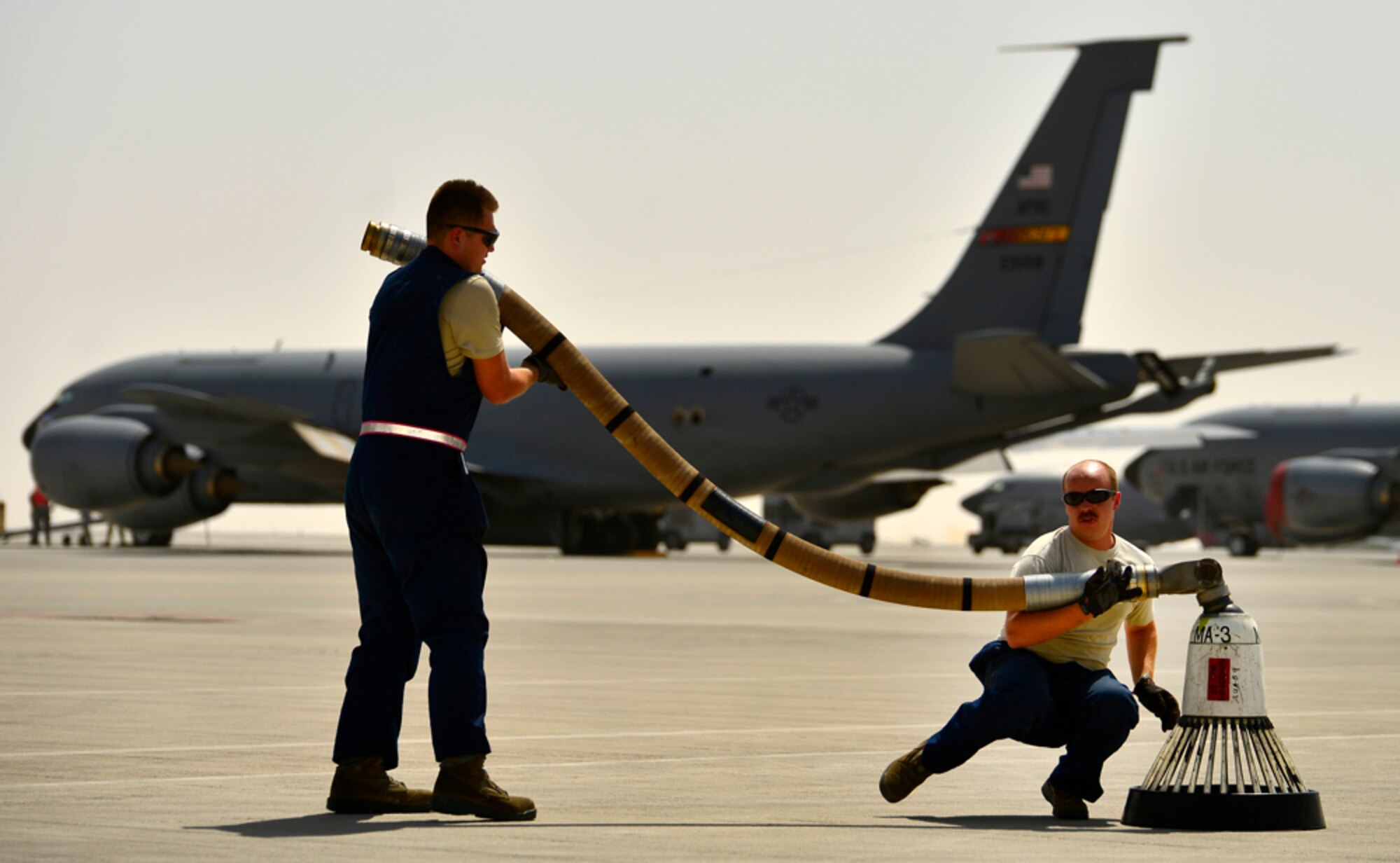 Airman 1st Class Joseph Swartz and Staff Sgt. Casey VanDeWeert, 340th Expeditionary Aircraft Maintenance Unit KC-135 Stratotanker crew chiefs, replace the KC-135 drogue basket for routine maintenance, Aug. 5, 2014, Al Udeid Air Base, Qatar. Airmen who perform maintenance on the flight line here endure stifling heat, sand and wind to keep air refueling aircraft and a multitude of other airframes constantly taking off and landing day and night. (U.S. Air Force photo by Staff Sgt. Vernon Young Jr.)