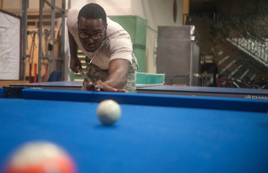 Senior Airman Martini Frazier, 51st Civil Engineer Squadron heating, ventilation, air condition and refrigeration journeyman, shoots a game of pool at Osan AB, Republic of Korea, Aug. 20, 2014. During lunch breaks, members of the shop would play pool or ping pong. (U.S. Air Force photo by Senior Airman Matthew Lancaster)