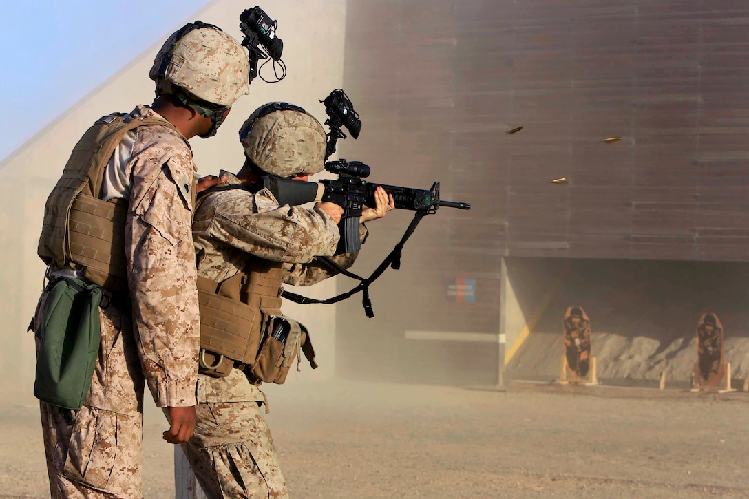 U.S. Marine Sgt. Lonnie Smith Jr., left, grips the back of a Marine’s plate carrier to provide support as he engages his target during training at a range on Camp Bastion in Afghanistan's Helmand province, Aug. 19, 2014. Smith is a flight equipment technician assigned to Heavy Helicopter Squadron 366.