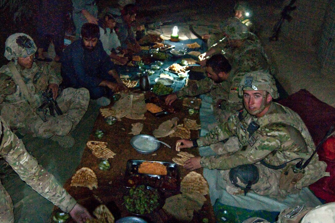 U.S. Army 2nd Lt. Trevor Hanson and his platoon eat dinner with Afghan police after an evening of patrols in Morghan Kachah village in Afghanistan's Kandahar province, Aug. 18, 2014. Hanson, a platoon leader, is assigned to the 4th Infantry Division's Company C, 1st Battalion, 12th Infantry Regiment, 4th Infantry Brigade Combat Team.