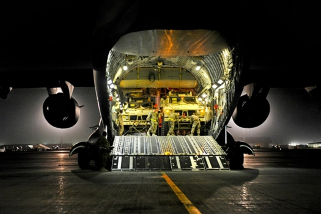 A U.S. airman guides a driver as they load a mine-resistant, ambush-protected all-terrain vehicle into a C-17 Globemaster III aircraft on Bagram Airfield, Afghanistan, Aug. 11, 2014.