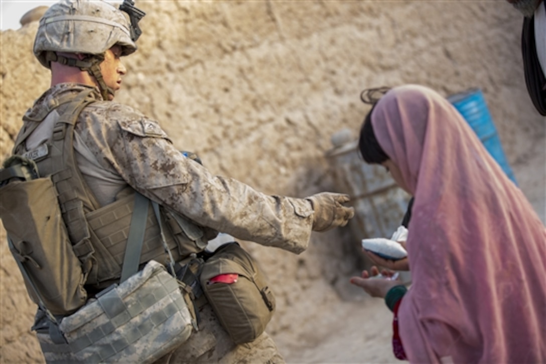 U.S. Marine Corps Lance Cpl. Bo Baker hands out candy to local children during a security patrol in Nad Ali district in Helmand province, Afghanistan, Aug. 11, 2014. Baker is a rifleman assigned to Bravo Company, 1st Battalion, 2nd Marine Regiment. 