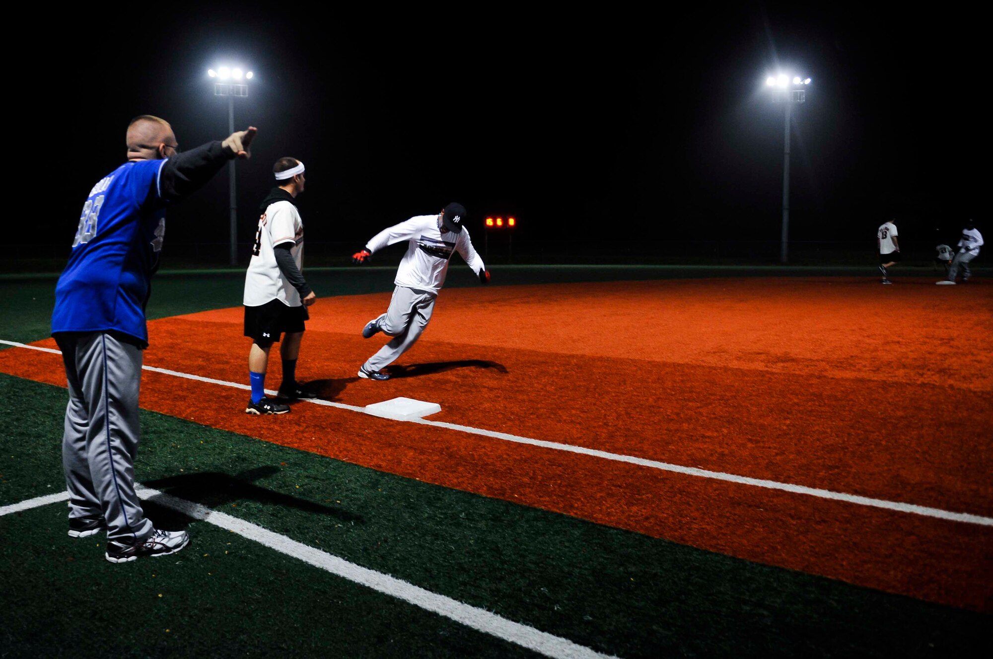 Philip Bouchard, 51st Security Forces Squadron, directs Jarred Alford, 51st SFS, home during the sixth inning of the intramural softball championship game on Osan Air Base, Republic of Korea, Aug. 21, 2014. The 51st SFS team defeated the 51st Operations Support Squadron team 18-8. (U.S. Air Force photo/Senior Airman David Owsianka)